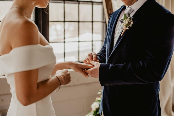 A groom sliding a ring onto a bride’s finger