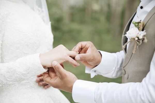 A groom putting a wedding ring on the bride’s finger