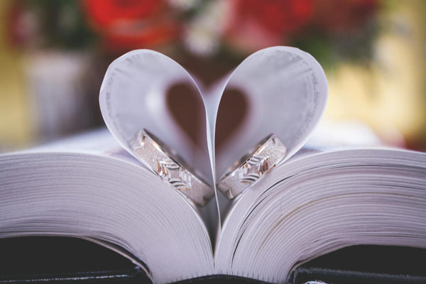 Two wedding rings in the pages of a book folded like a heart