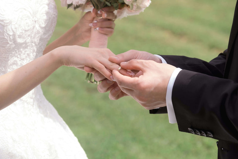 A groom putting a wedding ring on the bride’s finger